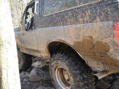 1991 Ford Bronco - This 1991 Ford Bronco is navigating a rocky, wooded trail, covered in mud.