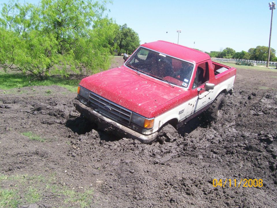 1988 Ford Bronco stuck in mud, 3q-front view, red and white