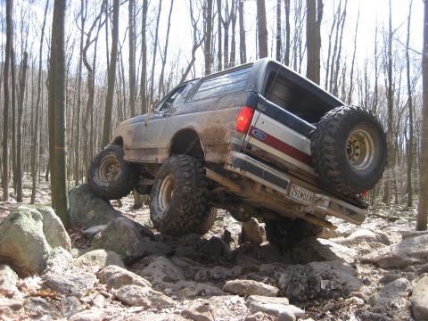 1991 Ford Bronco - Ford Bronco navigating a challenging rocky obstacle on an off-road trail.