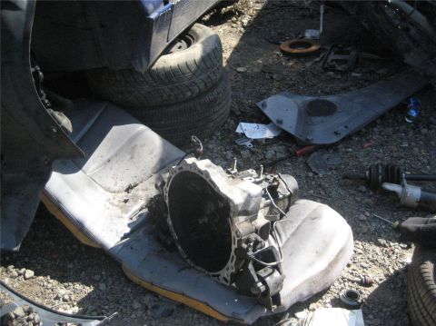 1993 Ford Probe - Junkyard scene with a car transmission and seats as the main focus.