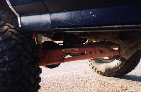 1988 Ford Bronco - Underside view of a dark blue Ford Bronco, showing its heavy-duty off-road tires and suspension.