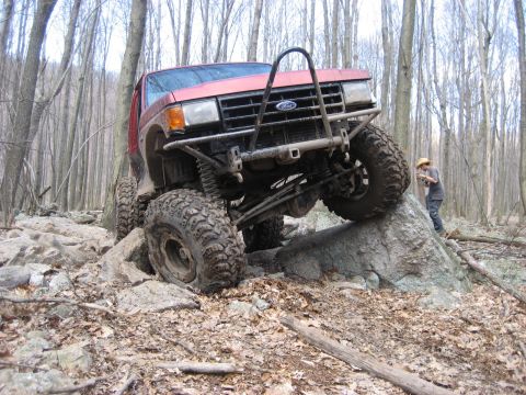 1991 Ford Bronco - This modified SUV navigates a rocky trail through a wooded area.