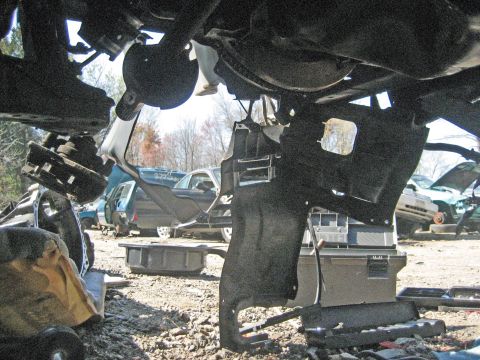 1993 Ford Probe - This photo shows the underside of a vehicle, with various parts and other cars visible in a junkyard setting.