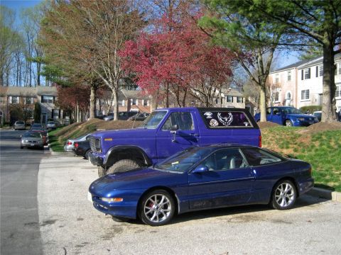 1993 Ford Probe - A blue 1993 Ford Probe is parked in front of a purple Ford Bronco.