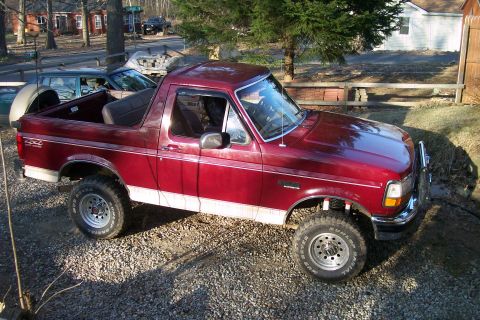 1993 Ford Bronco - This 1993 Ford Bronco is shown in a gravel lot with trees and houses in the background.