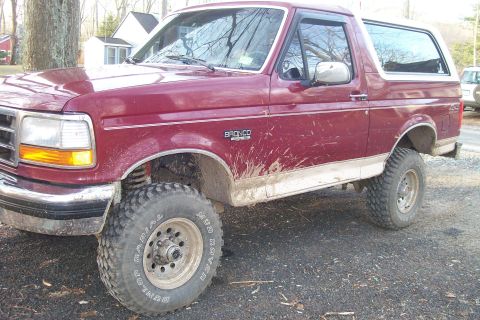 1993 Ford Bronco - Maroon 1993 Ford Bronco with lifted suspension and off-road tires, covered in mud.