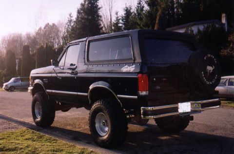 1988 Ford Bronco - Rear view of a black 1988 Ford Bronco with a lifted suspension and spare tire mounted.