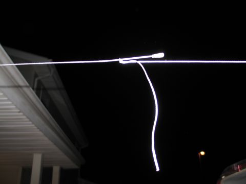 1995 Ford Bronco - Nighttime long-exposure photo showing bright overexposed wires or cables stretched horizontally against a black sky, with the edge of a whi…