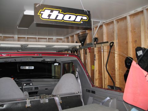 1995 Ford Bronco - Looking forward from the rear cargo area of a red Ford truck with its removable top off, showing gray front bucket seats, the dash with sli…