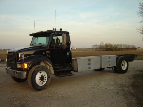 1992 Ford Bronco - International truck chassis with toolboxes parked outdoors on a dirt road.