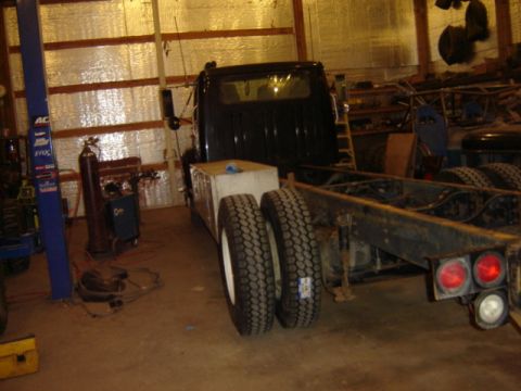 1992 Ford Bronco - Chassis of a truck, showing the rear axle and dual wheels, inside a workshop.