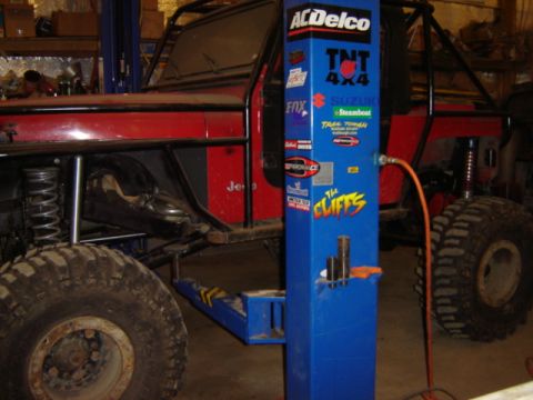 1992 Ford Bronco - A modified Jeep is shown on a lift in a garage, with a blue service column nearby.