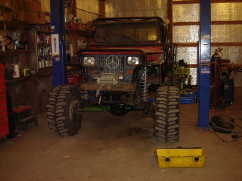 1992 Ford Bronco - A red Jeep Wrangler is shown on a lift in a garage, equipped with off-road tires and a winch.