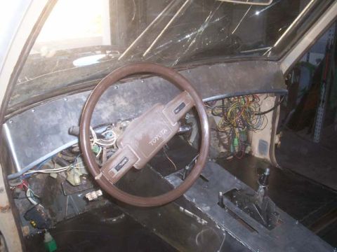 1982 Toyota 4Runner - The interior of a 1982 Toyota 4Runner displays a cluttered dashboard with exposed wiring and a prominent Toyota logo on the steering wheel.