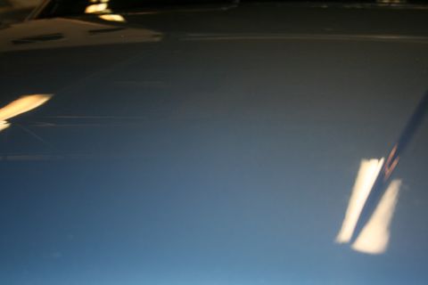 1990 Ford Mustang - The smooth surface of the car's hood reflects overhead lighting.
