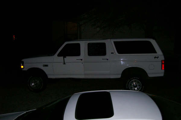 Side view of a white 1992 Ford C-350 Centurion Conversions pickup with camper shell
