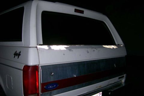 1992 Ford C-350 (Centurion Conversions) - The rear of a white Ford Bronco shows some paint wear on the tailgate and a prominent Ford emblem.