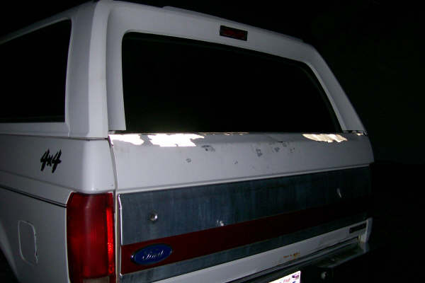 Rear view of a white Ford Bronco with 4x4 badging and a red stripe on the tailgate