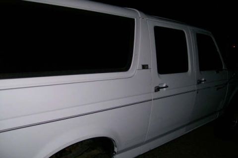 1992 Ford C-350 (Centurion Conversions) - A white van with tinted windows is seen from the side, a subtle pinstripe along its body.