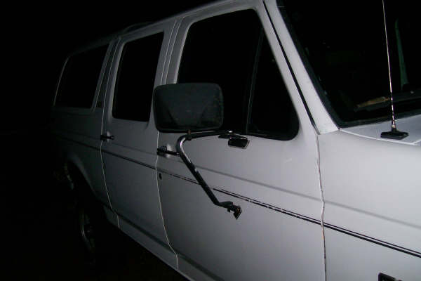 Side view of a white van with tinted windows and a large side mirror