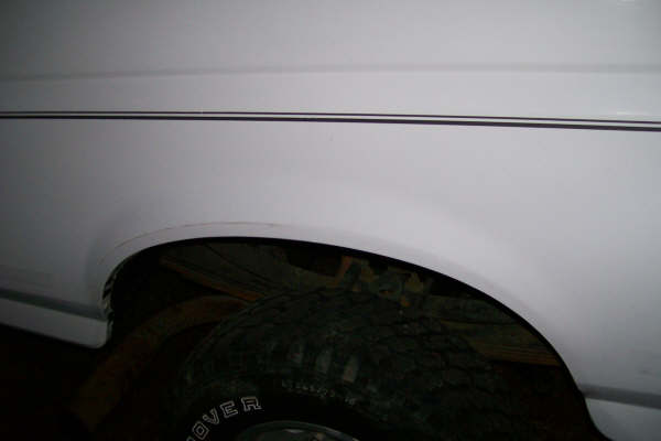 White vehicle side panel and rear wheel arch with off-road tire showing white 'ROVER' lettering