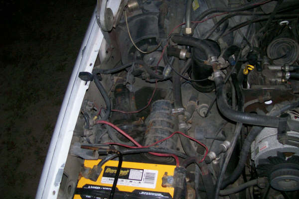 Engine bay with yellow battery and black hoses