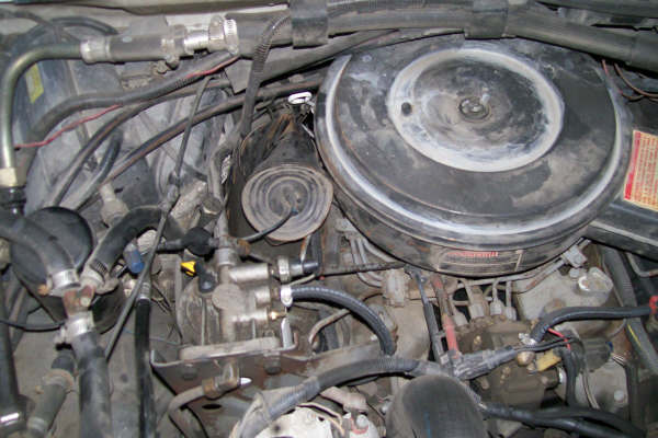 Engine bay with air cleaner housing, hoses, and engine components visible. Supermotors.net watermark present