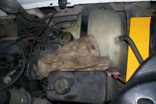 Engine bay with fluid reservoirs, hoses, and a rag