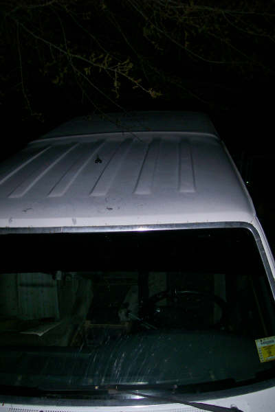 1992 Ford C-350 (Centurion Conversions) - The top of a white van is visible, with raised ribs on the roof. The image is dark and taken at night.