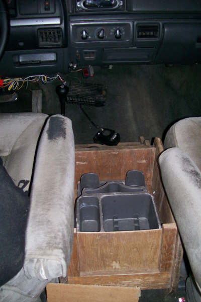 1992 Ford C-350 (Centurion Conversions) - The interior of a truck cab is shown, focusing on the dashboard and a custom wooden console with a storage organizer.