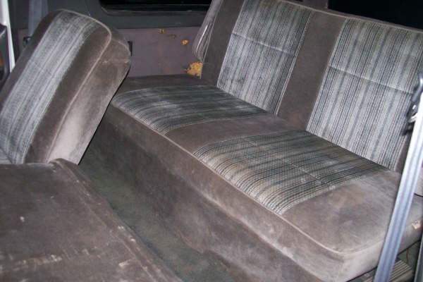 Rear bench seat in brown velour with striped cloth inserts inside an older vehicle