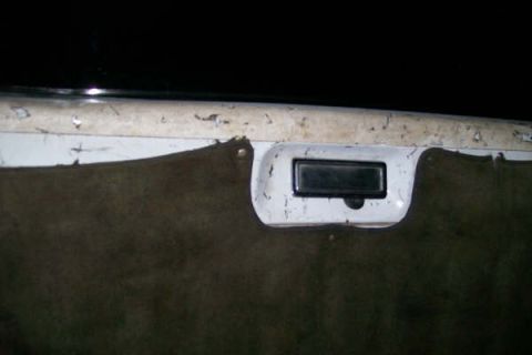 1992 Ford C-350 (Centurion Conversions) - Close-up of a vehicle's interior door panel, showing a black handle and worn white trim.