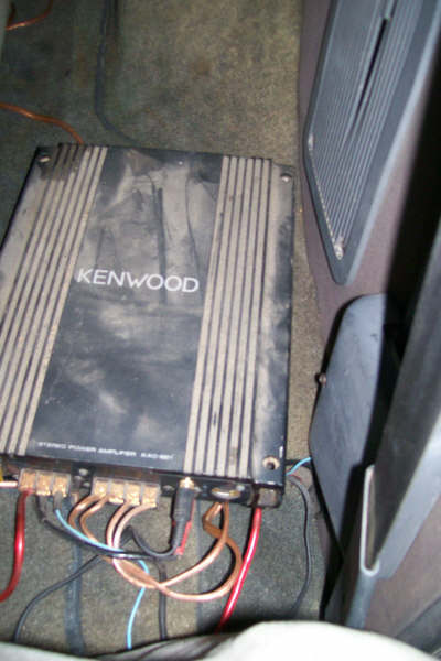 1992 Ford C-350 (Centurion Conversions) - A Kenwood stereo amplifier is visible on the floor of a vehicle, with wiring connected.