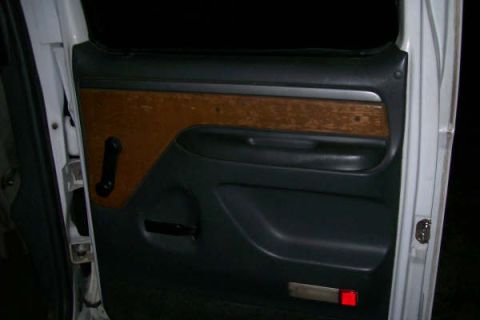 1992 Ford C-350 (Centurion Conversions) - Close-up of a truck's interior door panel, showing wood grain trim and black accents.