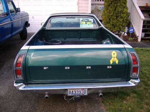 1972 Ford Ranchero - Straight-on rear view of a dark green Ford Ranchero in a driveway, showing the FORD-lettered tailgate, chrome bumper with dual exhaust tips…