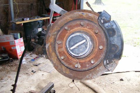 1988 Ford Bronco - Close-up of a rusty Dana 60 front axle hub and rotor assembly, likely removed for repair or maintenance.