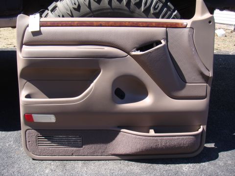 1996 Ford Bronco - This is a tan door panel from a 1996 Ford Bronco, wood trim and a storage pocket.