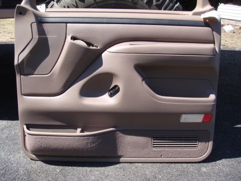 1996 Ford Bronco - A close-up view of a vehicle's interior door panel, showing its storage compartments and textured surface.