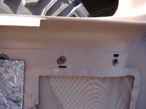 1996 Ford Bronco - Close-up of a tan interior door panel, showing mounting points and a speaker grille.