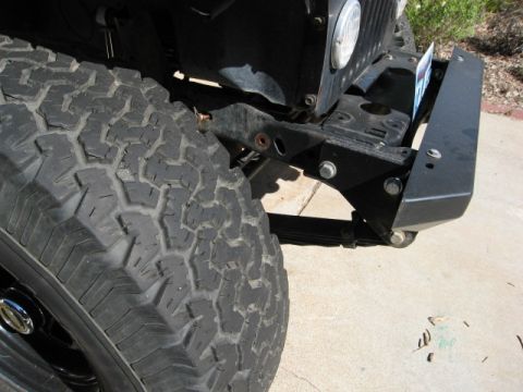 1986 Ford Bronco - Close-up of a Jeep CJ's front tire, bumper, and grille area.
