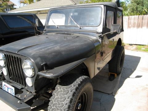 1986 Ford Bronco - This Jeep CJ7 is parked in a driveway next to another vehicle.