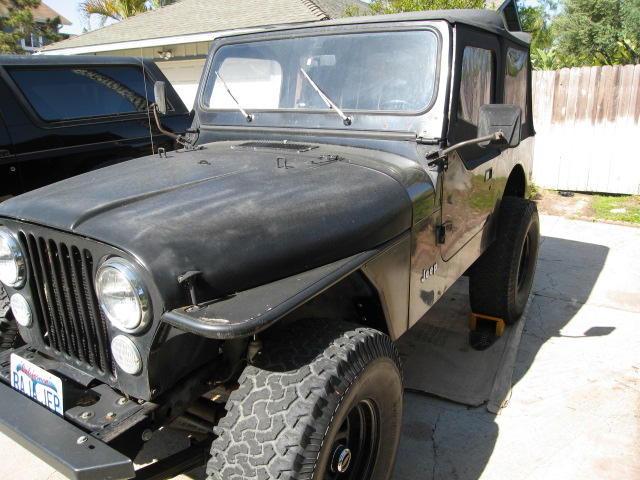 Black Jeep CJ7 with soft top, parked next to a black SUV