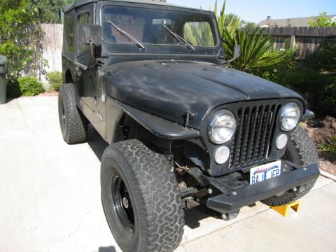 1986 Ford Bronco - This black Jeep CJ7 is shown from a three-quarter front angle, off-road tires and a soft top.
