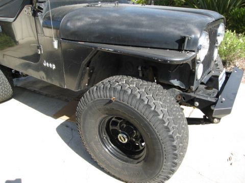1986 Ford Bronco - Front quarter view of a black Jeep CJ showing its grille, fender, and tire.