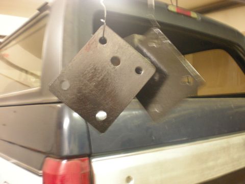 1993 Ford Bronco - Two metal brackets are suspended by wires above the tailgate of a pickup truck.