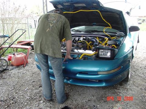 1993 Ford Probe - Man works on the engine of a teal 1993 Ford Probe in a driveway.