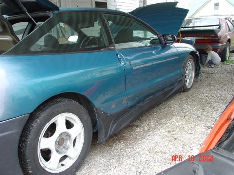 1993 Ford Probe - A teal 1993 Ford Probe is parked outside with its hood and trunk open, alongside another vehicle.
