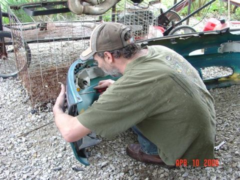 1993 Ford Probe - A man is seen working on a detached car bumper in an outdoor setting.