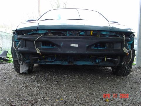 1993 Ford Probe - Front view of a teal car with its bumper removed, revealing the underlying structure and wiring.