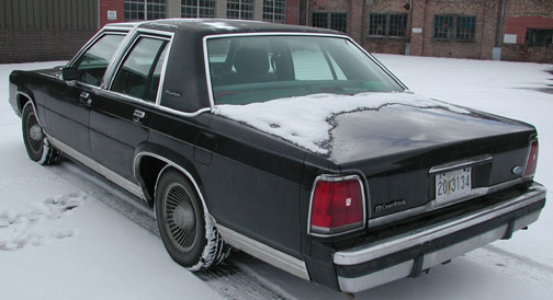 Rear three-quarter of black Ford LTD Crown Victoria sedan with snow on trunk